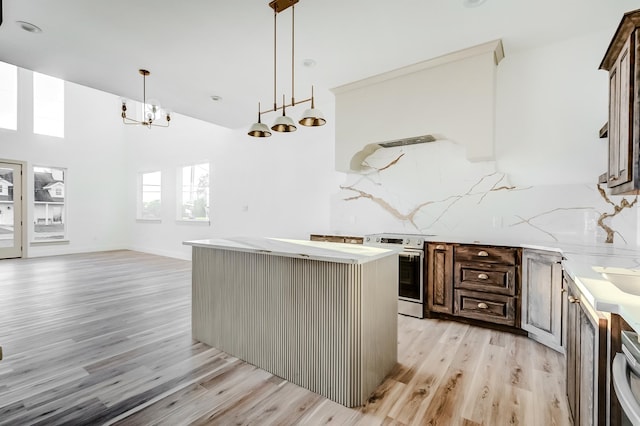 kitchen with tasteful backsplash, stainless steel range, dark brown cabinets, a center island, and light hardwood / wood-style floors