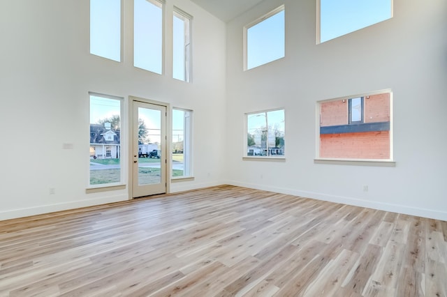 interior space with a towering ceiling and light hardwood / wood-style flooring