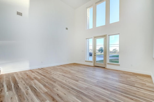 unfurnished room featuring a high ceiling and light hardwood / wood-style flooring