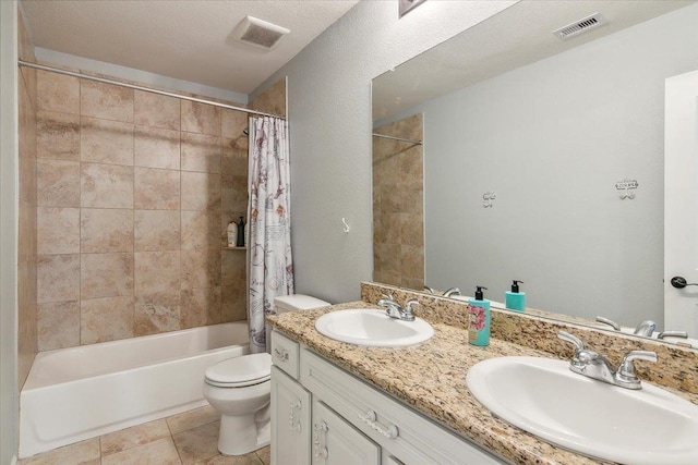 full bathroom with a textured ceiling, vanity, shower / bath combo with shower curtain, tile patterned flooring, and toilet