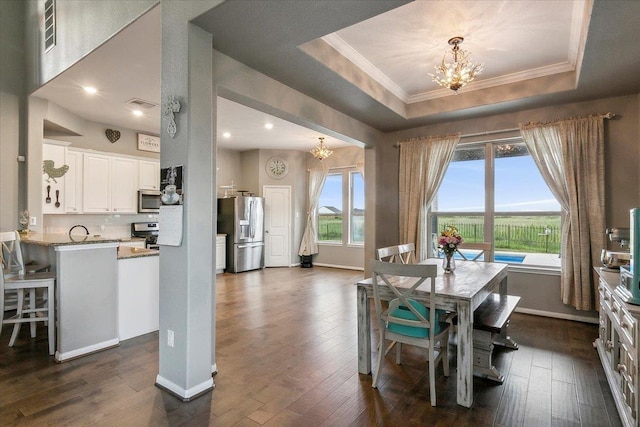 dining space with a chandelier, a tray ceiling, dark hardwood / wood-style floors, and ornamental molding