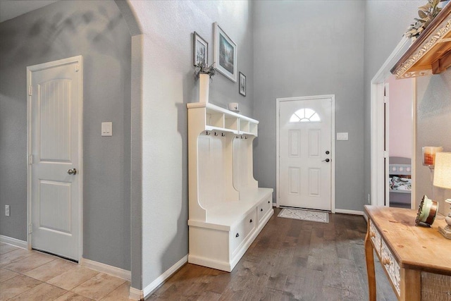 mudroom featuring wood-type flooring and a towering ceiling