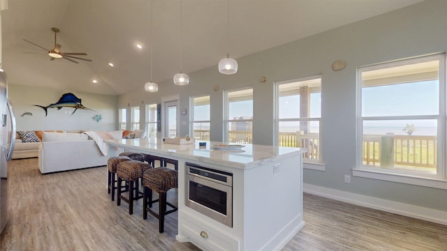335 Atkinson, Crystal Beach, TX 77650 - kitchen featuring open floor plan, light stone counters, a kitchen breakfast bar, light wood-type flooring, and a center island