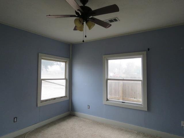 spare room with plenty of natural light, light carpet, and ceiling fan