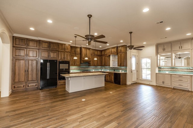 kitchen with a center island, tasteful backsplash, wood-type flooring, ornamental molding, and black appliances