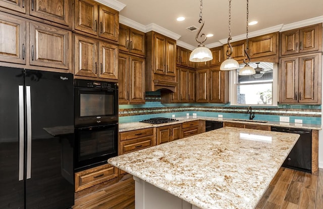 kitchen with sink, light stone counters, hanging light fixtures, a kitchen island, and black appliances