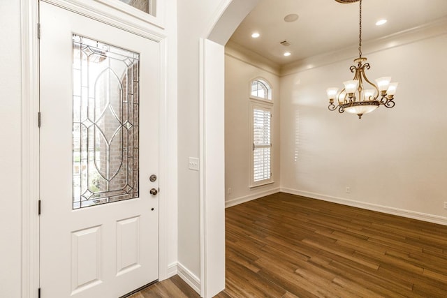 entryway featuring crown molding, a chandelier, and dark wood-type flooring