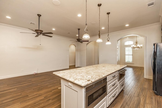 kitchen featuring pendant lighting, black refrigerator, stainless steel microwave, white cabinets, and a kitchen island