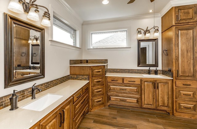 bathroom with crown molding, vanity, hardwood / wood-style flooring, ceiling fan, and decorative backsplash