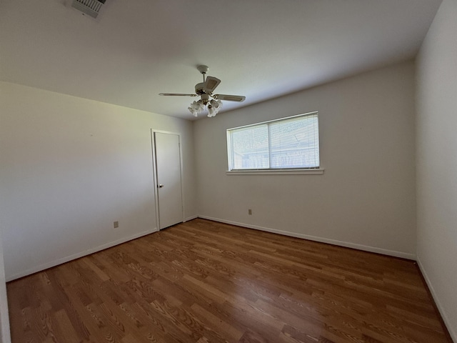 unfurnished room featuring ceiling fan, baseboards, wood finished floors, and visible vents