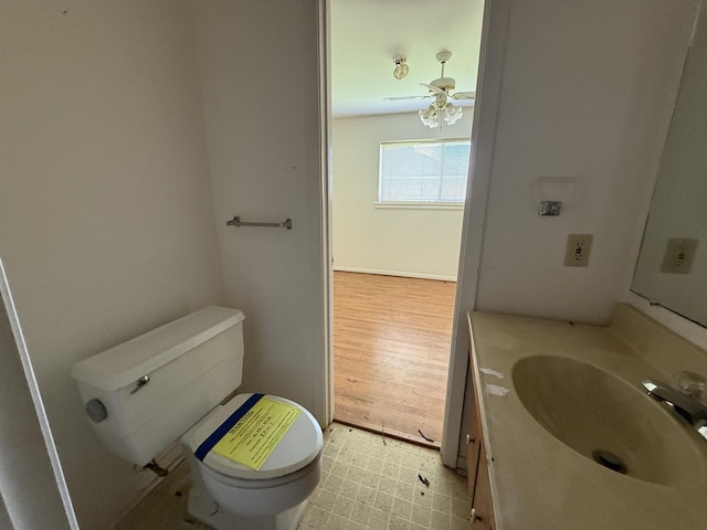 half bathroom with vanity, ceiling fan, and toilet