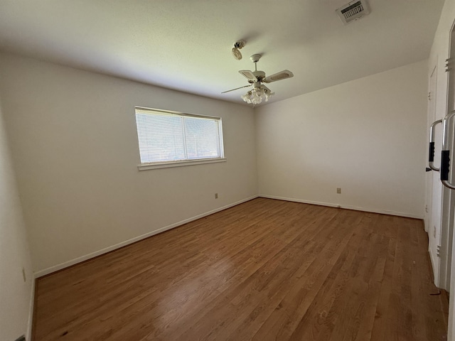 empty room with ceiling fan, baseboards, wood finished floors, and visible vents