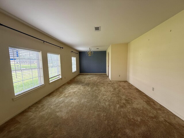 carpeted spare room with visible vents, baseboards, and an inviting chandelier