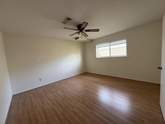 spare room featuring wood finished floors, visible vents, baseboards, and ceiling fan