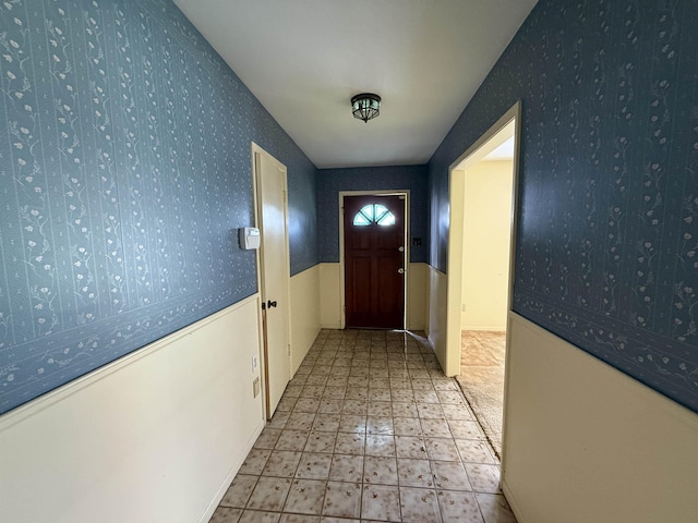 entryway featuring wallpapered walls, tile patterned floors, and wainscoting