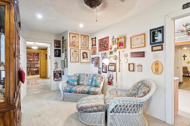 living area featuring light carpet, ceiling fan, and a textured ceiling