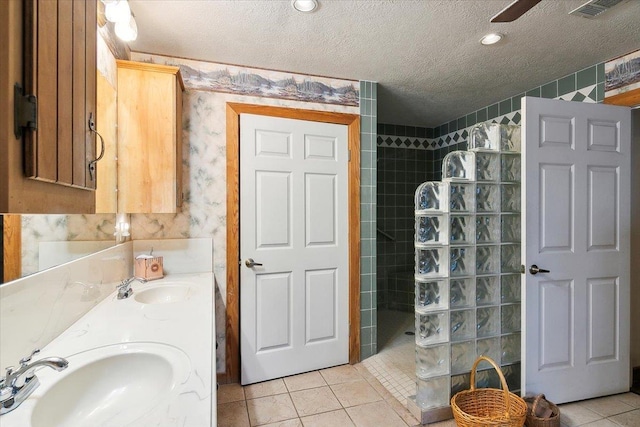 bathroom featuring tile patterned floors, vanity, tiled shower, and a textured ceiling