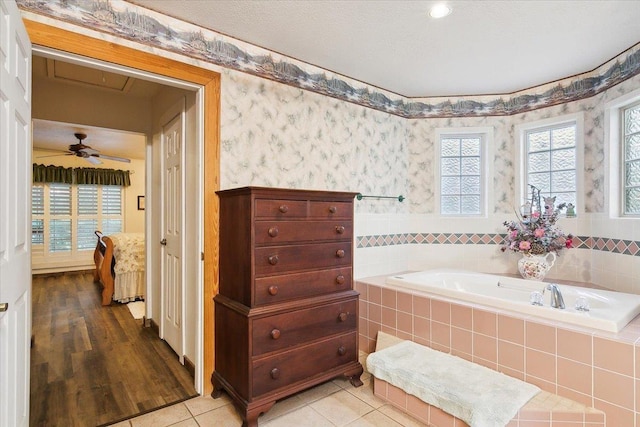 bathroom with tile patterned flooring, a textured ceiling, a relaxing tiled tub, and ceiling fan