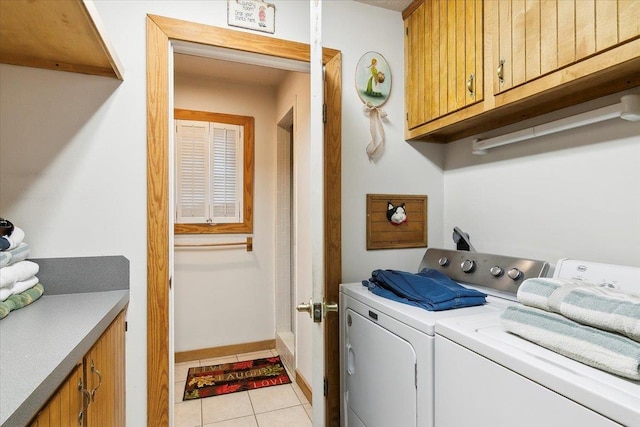 clothes washing area featuring light tile patterned flooring, cabinets, and washing machine and clothes dryer