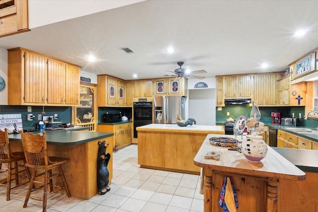 kitchen featuring ceiling fan, a center island, light tile patterned floors, and black appliances