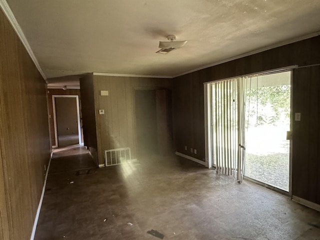 unfurnished room with visible vents, crown molding, and wood walls