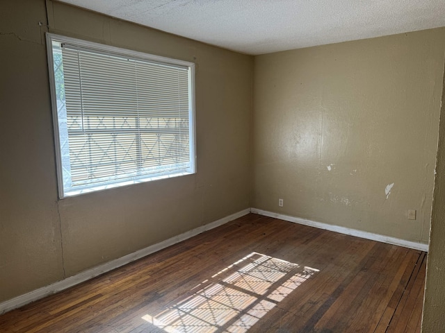 unfurnished room with a textured ceiling, baseboards, and hardwood / wood-style flooring