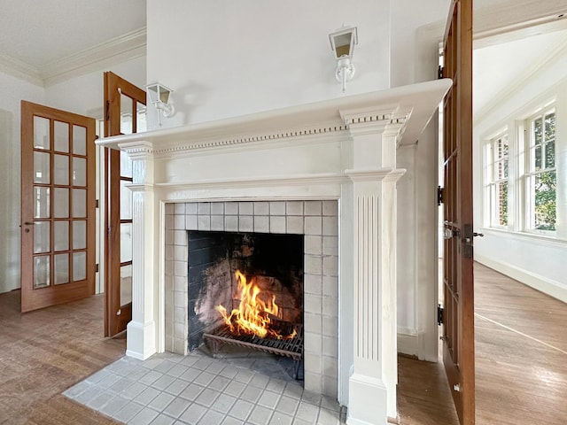 room details with ornamental molding, a tile fireplace, decorative columns, and wood finished floors