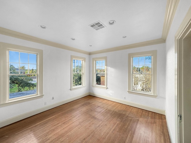 spare room with baseboards, visible vents, ornamental molding, wood finished floors, and recessed lighting