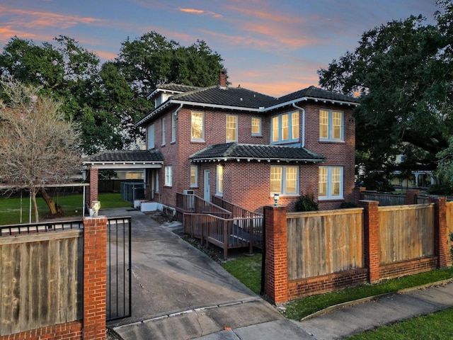 view of front facade featuring brick siding, a fenced front yard, and a chimney