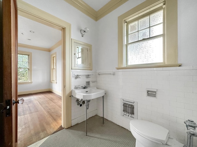 half bath with heating unit, tile walls, toilet, and crown molding