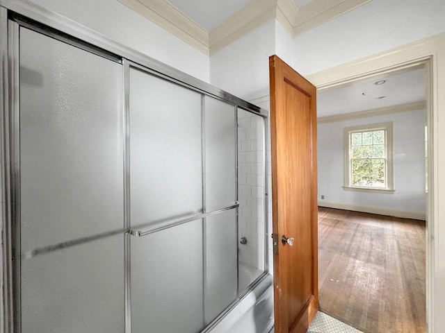 bathroom featuring combined bath / shower with glass door, crown molding, baseboards, and wood finished floors