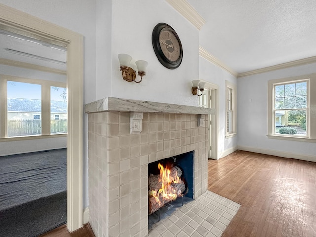 interior details with a textured ceiling, wood finished floors, baseboards, ornamental molding, and a brick fireplace