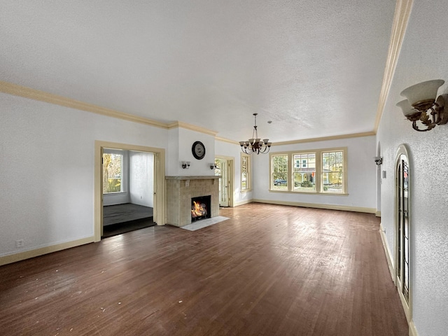 unfurnished living room with baseboards, a fireplace with flush hearth, ornamental molding, wood finished floors, and a chandelier