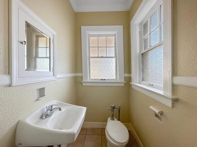 half bathroom featuring tile patterned flooring, baseboards, a sink, and a textured wall