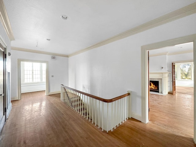 corridor with crown molding, baseboards, wood finished floors, and an upstairs landing