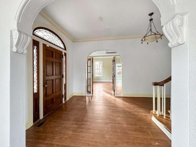 entryway featuring baseboards, visible vents, arched walkways, ornamental molding, and wood finished floors