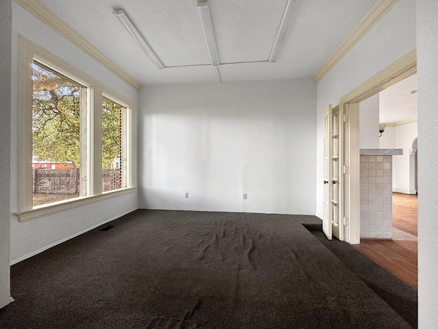 spare room with carpet floors, visible vents, and crown molding