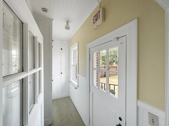 entryway featuring light carpet and crown molding