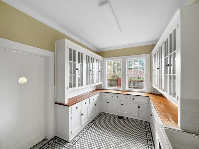 interior space featuring light floors, ornamental molding, and a sink