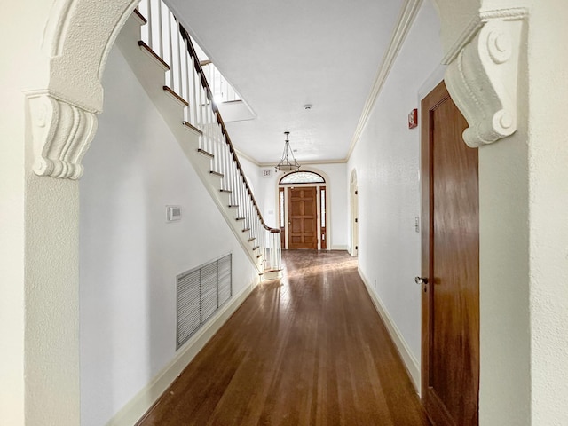 corridor featuring arched walkways, wood finished floors, visible vents, baseboards, and ornamental molding