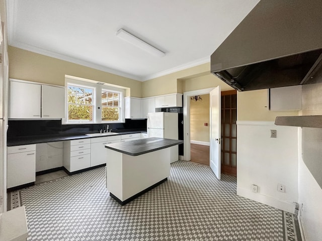 kitchen with ornamental molding, dark countertops, a sink, and range hood