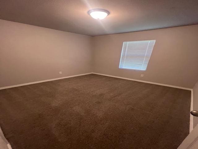 spare room featuring dark carpet