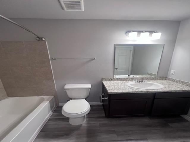 full bathroom with hardwood / wood-style flooring, vanity,  shower combination, and toilet