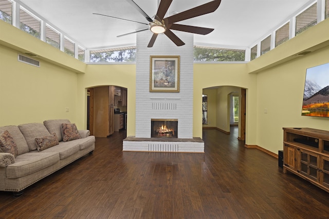 3042 Parish Cemetery Rd, Little Cypress, TX 77632 - living area featuring arched walkways, a towering ceiling, ceiling fan, wood finished floors, and a brick fireplace