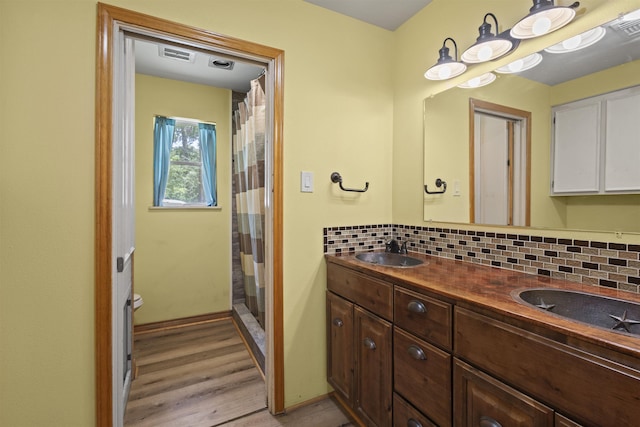 3042 Parish Cemetery Rd, Little Cypress, TX 77632 - full bath featuring tasteful backsplash, wood finished floors, double vanity, and a shower with shower curtain