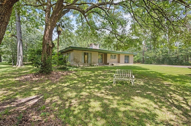 3042 Parish Cemetery Rd, Little Cypress, TX 77632 - single story home with a front lawn, a chimney, and brick siding