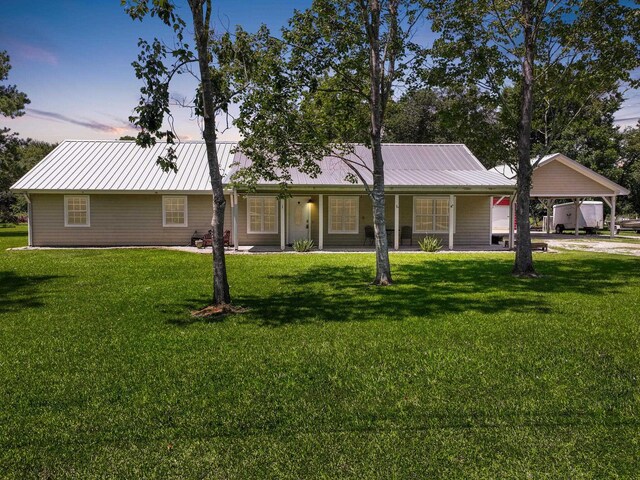 ranch-style house with metal roof, a carport, and a front yard