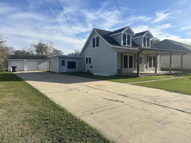 view of front of house with an outbuilding, covered porch, a front yard, and a garage