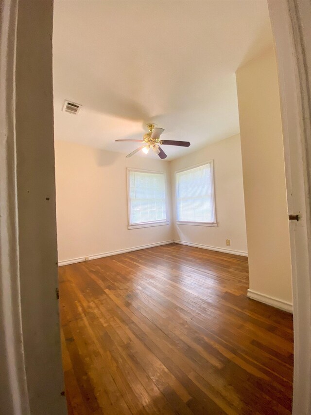 spare room with dark hardwood / wood-style flooring and ceiling fan