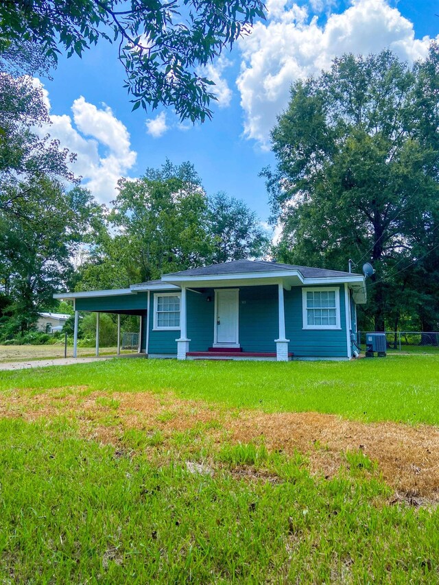view of front of house featuring a carport, central air condition unit, and a front yard